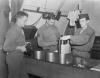 Photographic officers of the 390th Bomb Group develop combat rolls of film. Image stamped on reverse: ‘Keystone Press.’ [stamp], ‘Passed for publication 27 Aug 1943.’ [stamp] and ‘281033.’ [Censor no.] Printed caption on reverse: ' PHOTO MEN SERVE WITH FLYING FORTRESSES. When it comes to bombing, pictures tell the story. Skilled photographers serving with the U.S. 8th Air Force Flying Fortress Group are trained to get the pictures, process them and send prints and negatives to higher Headquarters - all on split-second schedule. Automatic cameras are installed in the Forts before take-off, each equipped with an intervalometer. Over the target the 'plane's radio operator merely flick a switch ... the camera does the rest, swapping consecutive shots at predetermined intervals. On return, photo men are on hand to meet the Forts. Films are rushed by Jeep to the Photo Laboratory, processed at high speed, then dispatched to Wing H by special courier. But mission shots are only ... of the photo section. It also handles everything from public relations and engineering to battle damage and identification pictures. This series of pictures shows the men of the Photo section of a Flying Fortress Group at work . U.S. Pool/F.KEYSTONE SG. Developing combat rolls of film. US POOL/ Keystone.'