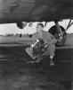 A ground crewman of the 390th Bomb Group unloads a combat camera from a B-17 Flying Fortress. Image stamped on reverse: ‘Keystone Press.’ [stamp], ‘Passed for publication 27 Aug 1943.’ [stamp] and ‘281019.’ [Censor no.] Printed caption on reverse: 'PHOTO MEN SERVE WITH FLYING FORTRESSES. When it comes to bombing, pictures tell the story. Skilled photographers serving with the U.S. 8th Air Force Flying Fortress Group are trained to get the pictures, process them and send prints and negatives to higher Headquarters - all on split-second schedule. Automatic cameras are installed in the Forts before take-off, each equipped with an intervalometer. Over the target the 'plane's radio operator merely flick a switch ... the camera does the rest, swapping consecutive shots at predetermined intervals. On return, photo men are on hand to meet the Forts. Films are rushed by Jeep to the Photo Laboratory, processed at high speed, then dispatched to Wing H by special courier. But mission shots are only ... of the photo section. It also handles everything from public relations and engineering to battle damage and identification pictures. This series of pictures shows the men of the Photo section of a Flying Fortress Group at work . U.S. Pool/F.KEYSTONE SG. Removing camera from plane.'